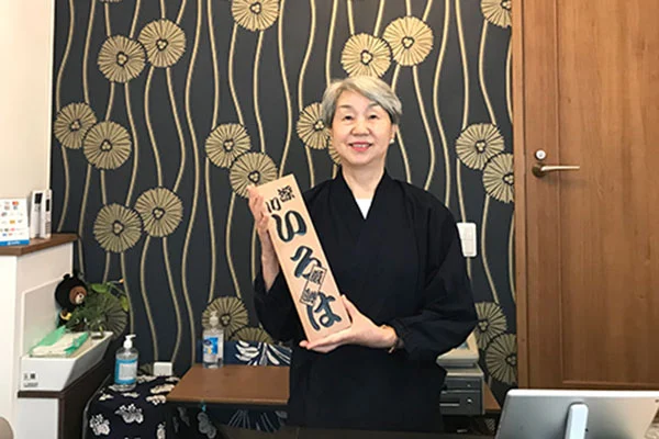 店内で「いろは」の看板を手にする店主